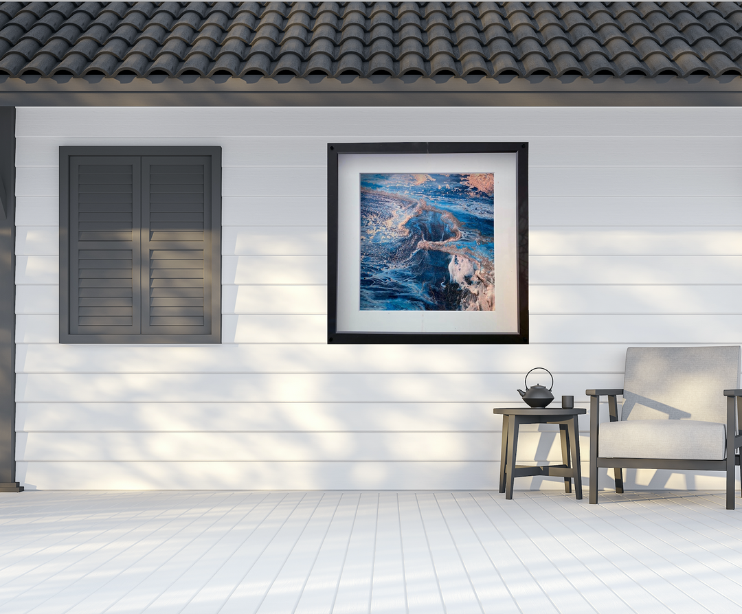 Framed abstract art on a white wall with a chair and small table below.