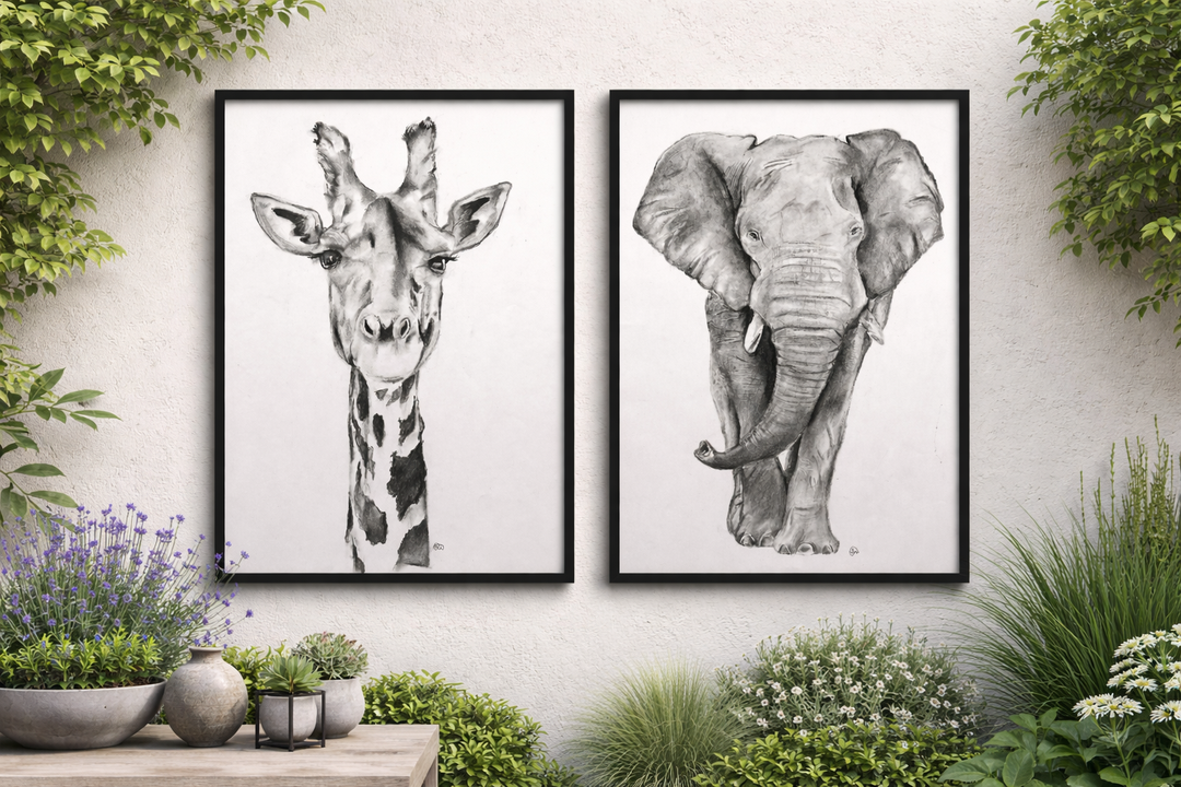 Two framed animal prints of a giraffe and an elephant on a wall with plants around.