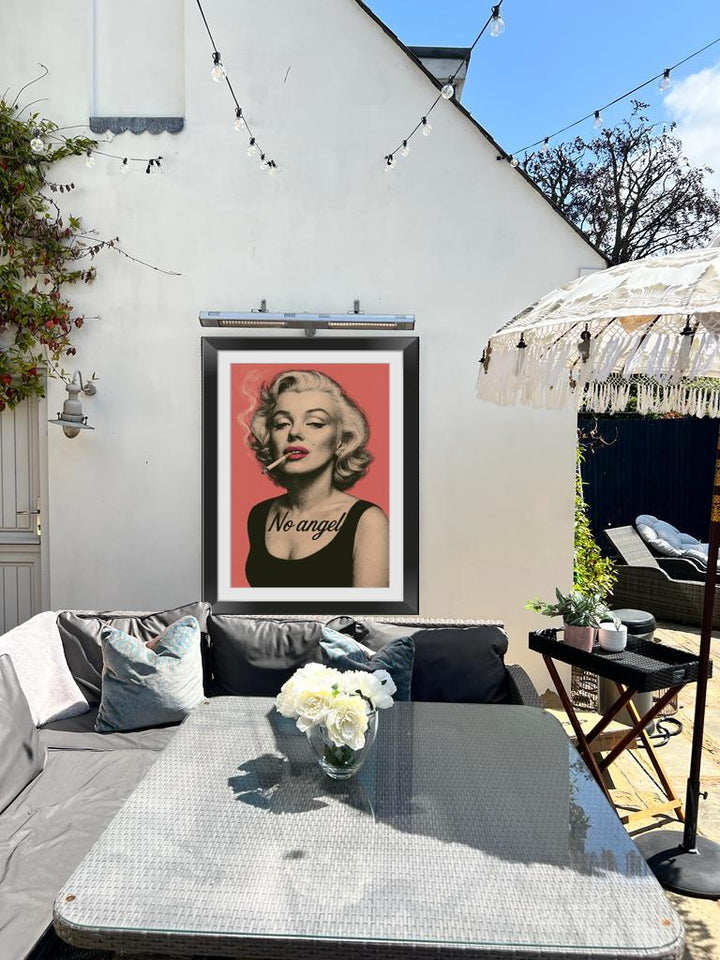 Outdoor patio with a poster of a famous person on a wall, a table with flowers, and a chair under an umbrella.