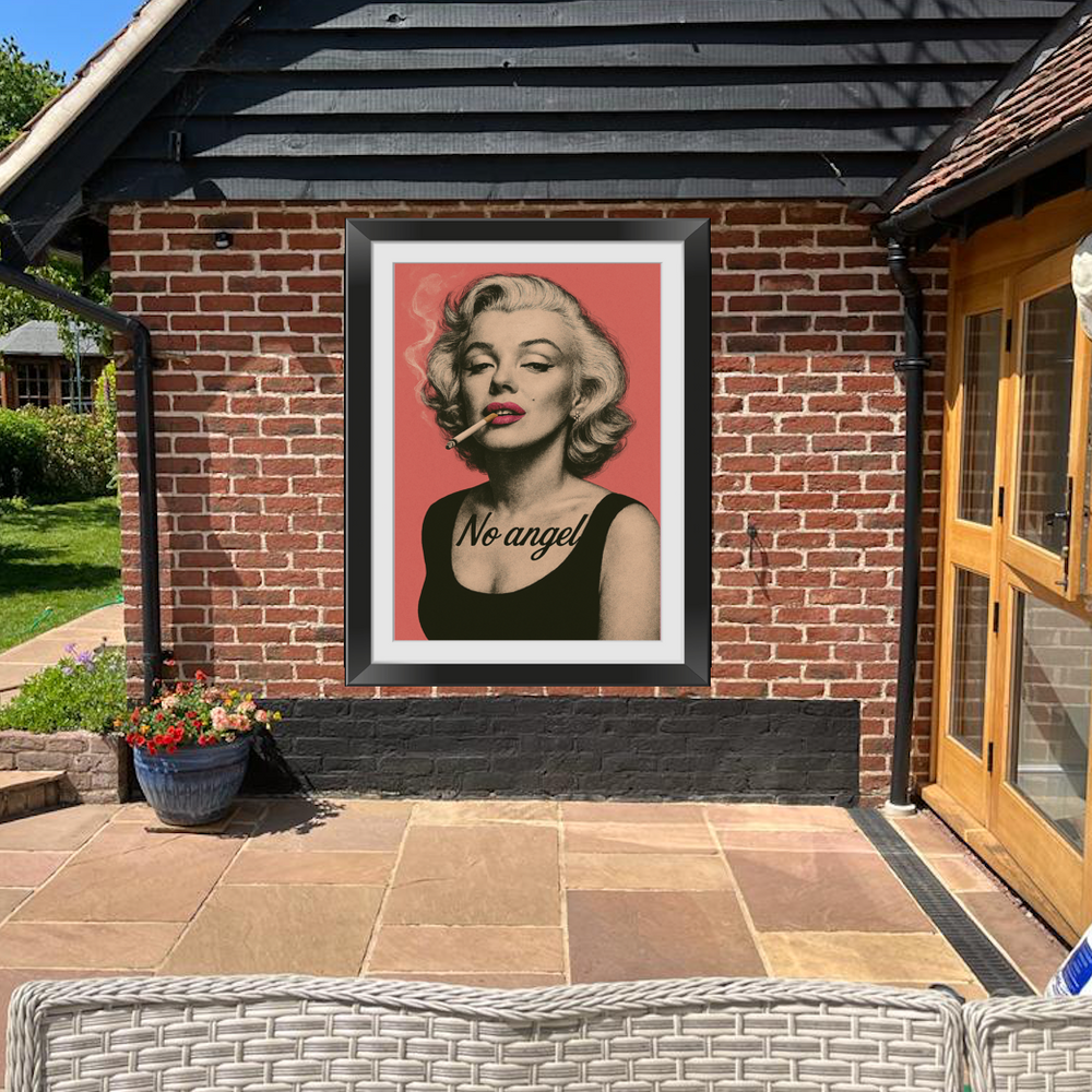 A framed outdoor acrylic print of Marilyn Monroe with the text 'No angel' on a rose background, displayed on a brick wall.