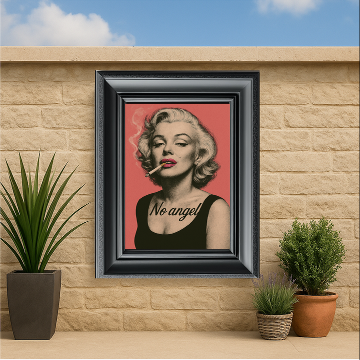 Framed artwork of a stylized portrait with 'No angel' text on a red background, displayed outdoors.