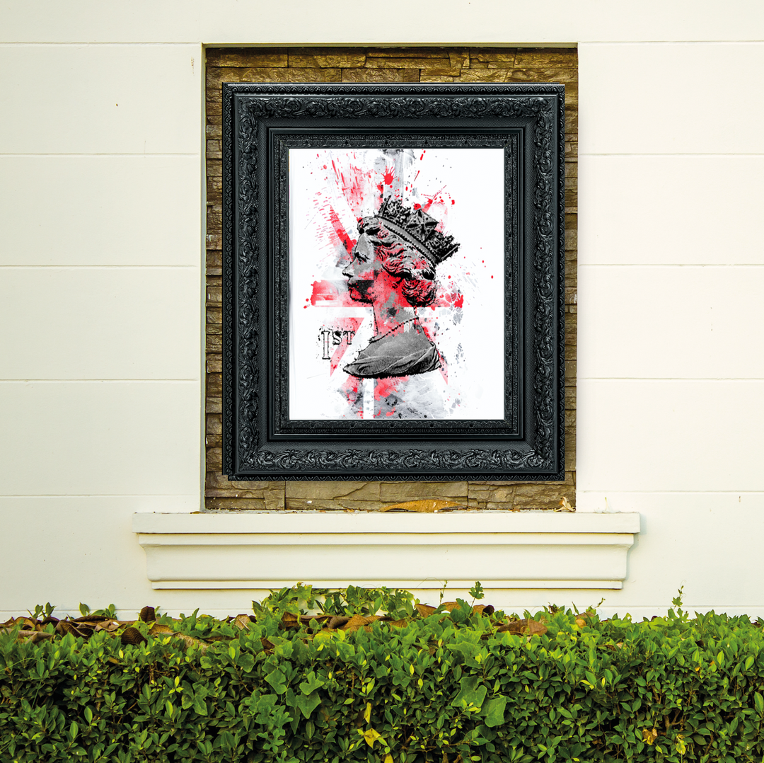Framed artwork with a black frame on a white wall above greenery